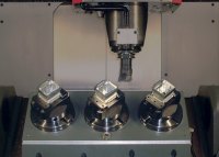 The compact size of CenterCompact vises allows more workpieces to fit in a machine. In this example, round QuickPoint base plates are used on a 3-station trunnion.